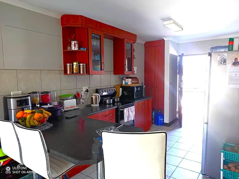 A functional kitchen featuring red cabinetry, dark countertops, tiled backsplash, and direct access to an outdoor area.