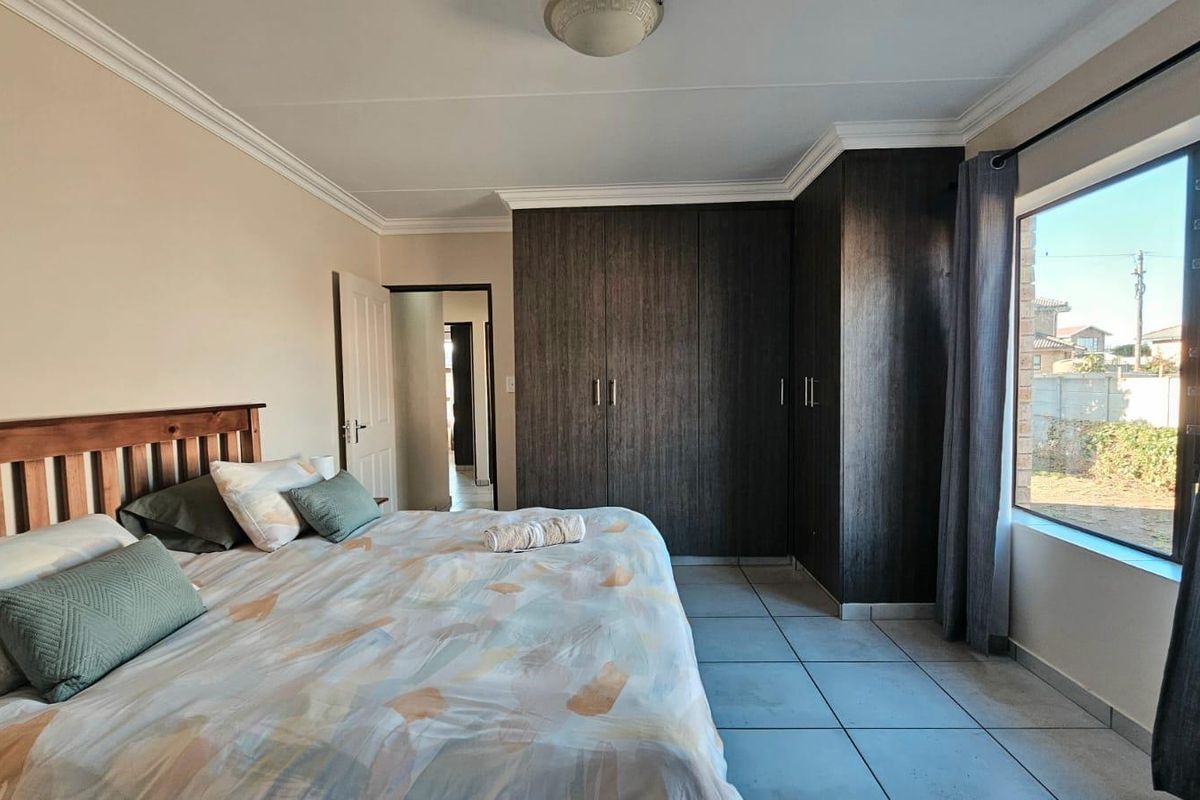A well-maintained bedroom featuring dark wood built-in cupboards, tiled flooring, and large windows allowing for natural light.