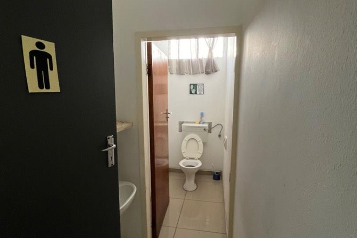A functional restroom facility featuring tiled flooring, a standard toilet, and a small hand basin, accessible via a doorway.