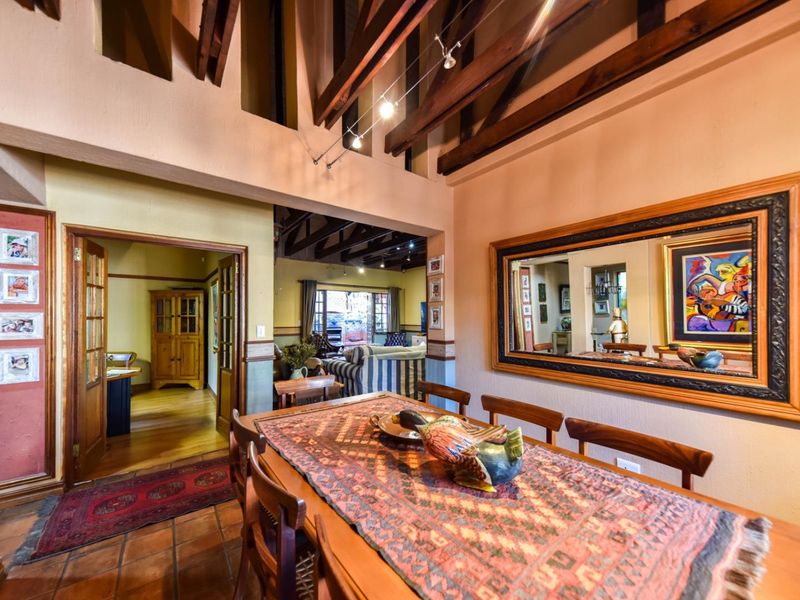 Spacious dining area featuring high vaulted ceilings with exposed timber beams, terracotta flooring, and an open-plan flow into the adjacent living space.