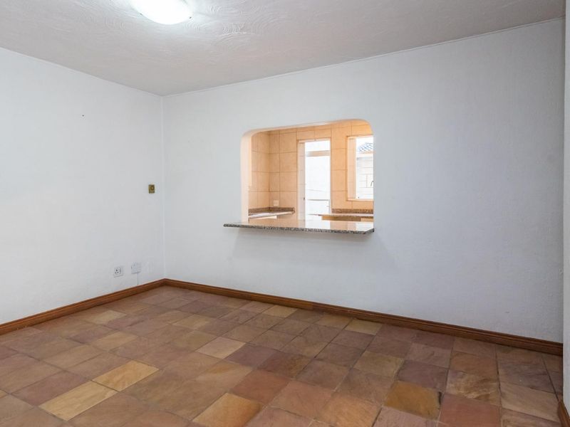 An empty living area featuring stone tile flooring and a convenient serving hatch with a granite breakfast bar connecting to the kitchen.