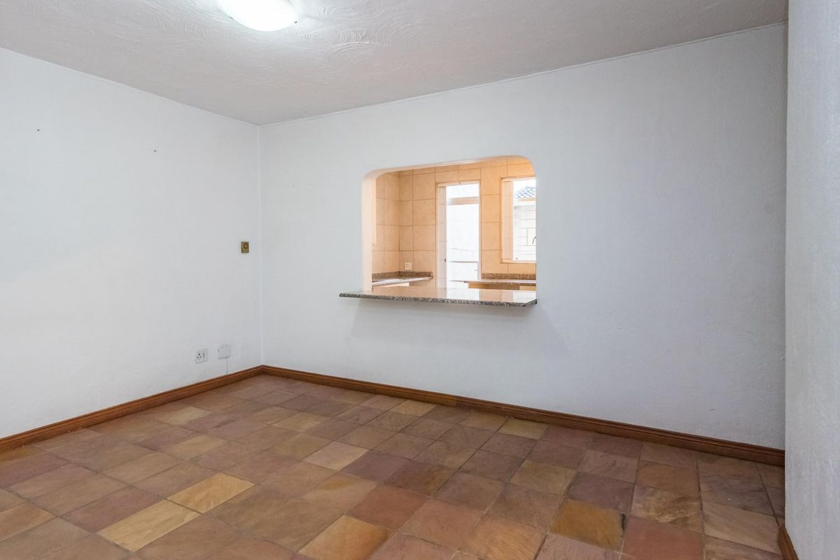 An empty living area featuring stone tile flooring and a convenient serving hatch with a granite breakfast bar connecting to the kitchen.