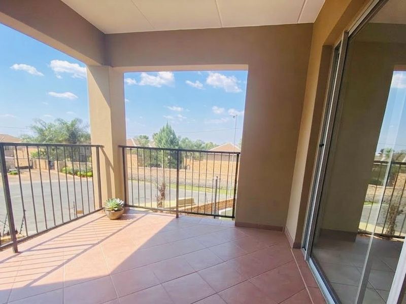 A covered balcony featuring tiled flooring, a metal balustrade, and sliding glass door access, offering an open outdoor space.