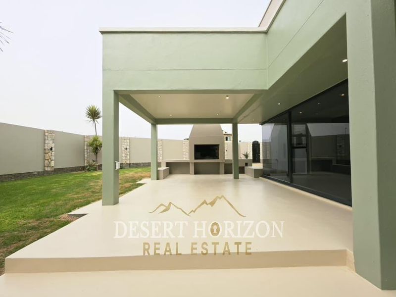 Spacious covered patio featuring a built-in braai, recessed lighting, and seamless access to the garden through large sliding glass doors.