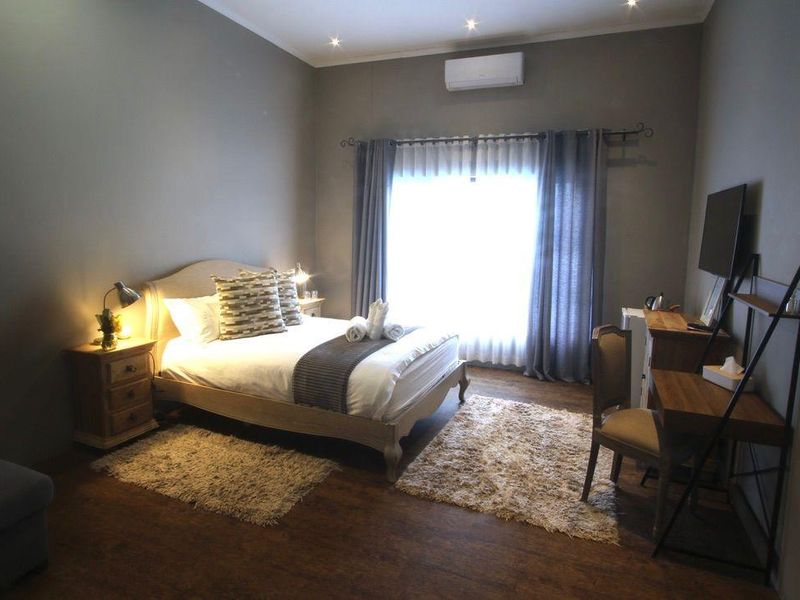 A well-maintained bedroom featuring laminate flooring, recessed downlighting, and a wall-mounted split-system air conditioning unit.