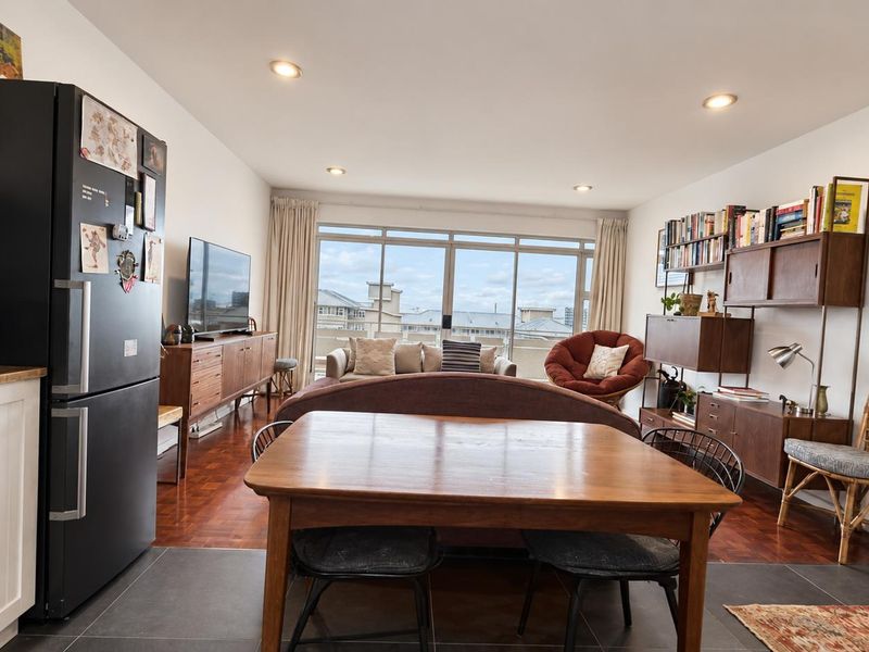 Open-plan living and dining area featuring parquet flooring, recessed lighting, and large sliding doors leading to an outdoor view.