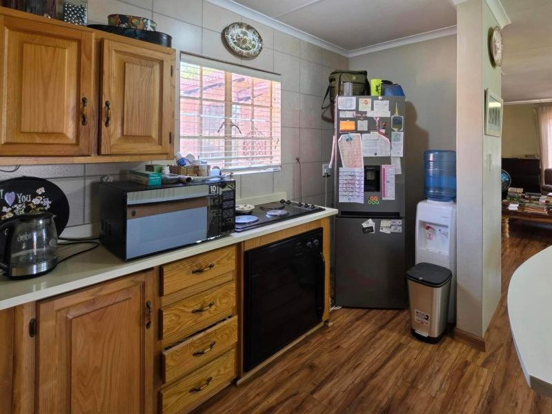 A functional kitchen featuring wooden cabinetry, laminate countertops, and built-in cooking appliances, with a view leading into the adjacent living area.
