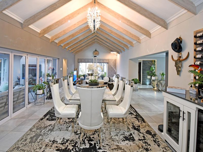 Spacious dining area featuring a dramatic vaulted ceiling with exposed timber rafters, tiled flooring, and seamless access to the outdoors via bi-fold glass doors.