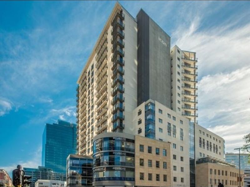 A modern multi-story apartment building featuring a glass facade and private balconies, showcasing contemporary urban architecture.