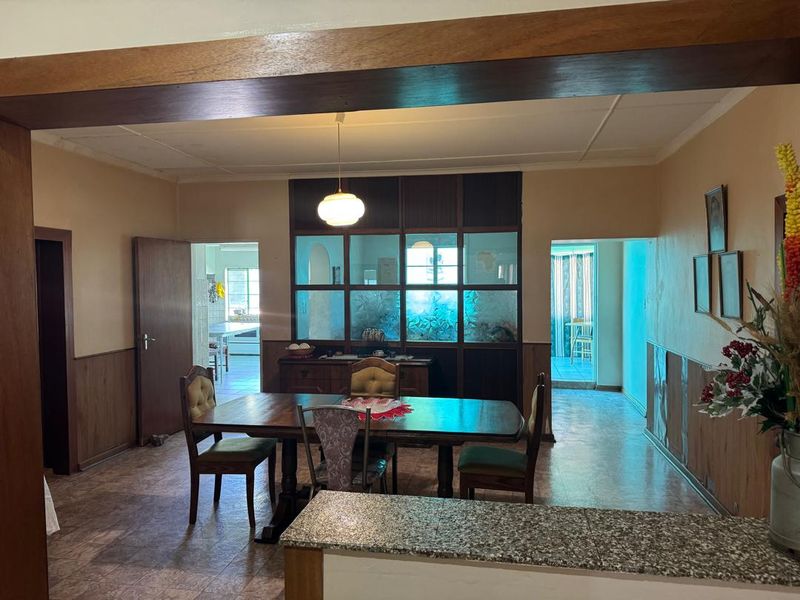 Open plan dining area featuring timber wall paneling, a decorative glass partition, and a granite-topped breakfast counter, connecting to adjacent living and kitchen spaces.