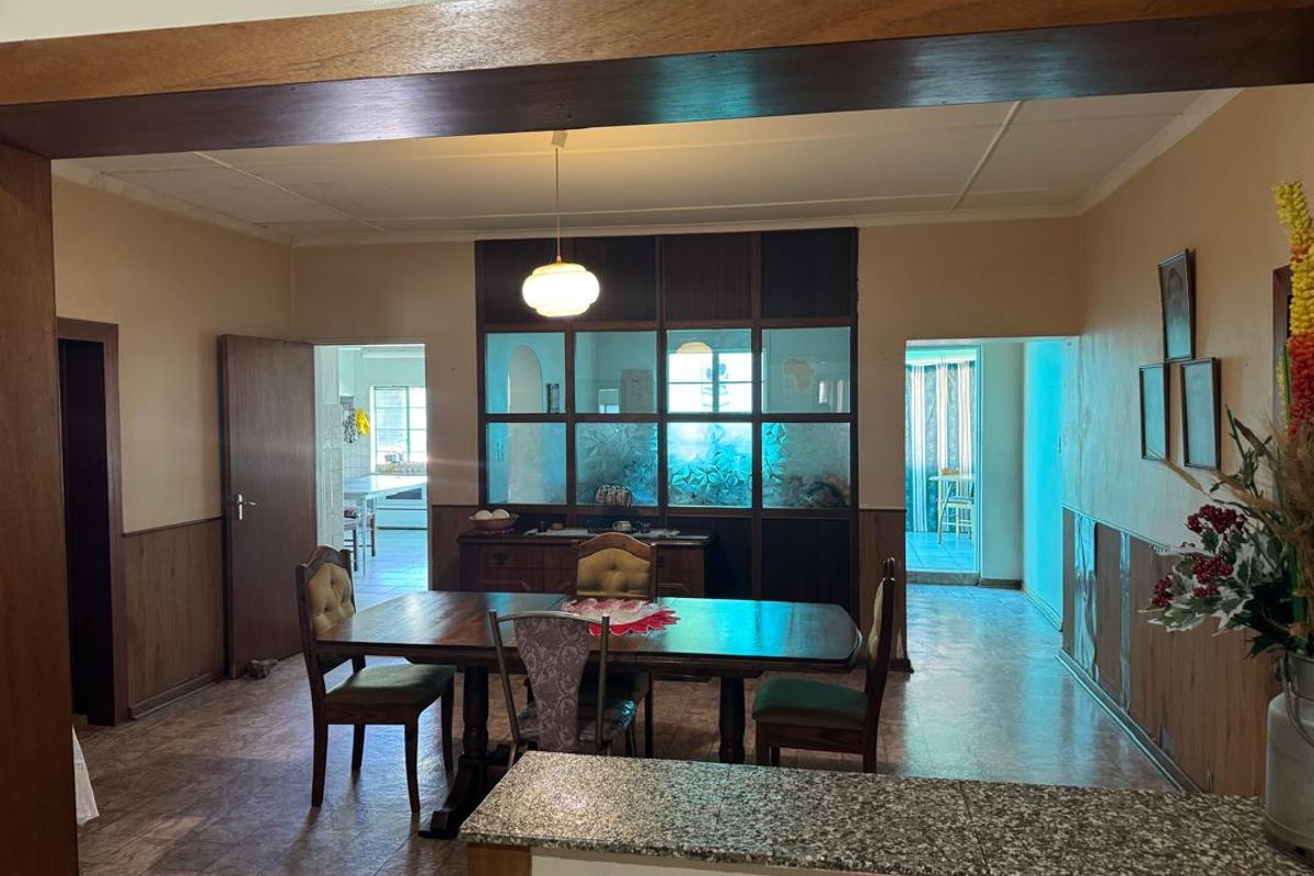 Open plan dining area featuring timber wall paneling, a decorative glass partition, and a granite-topped breakfast counter, connecting to adjacent living and kitchen spaces.