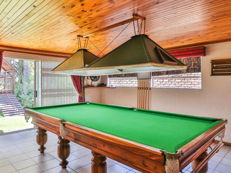 Spacious entertainment room featuring a timber ceiling, tiled floors, and direct access to the garden through sliding glass doors.