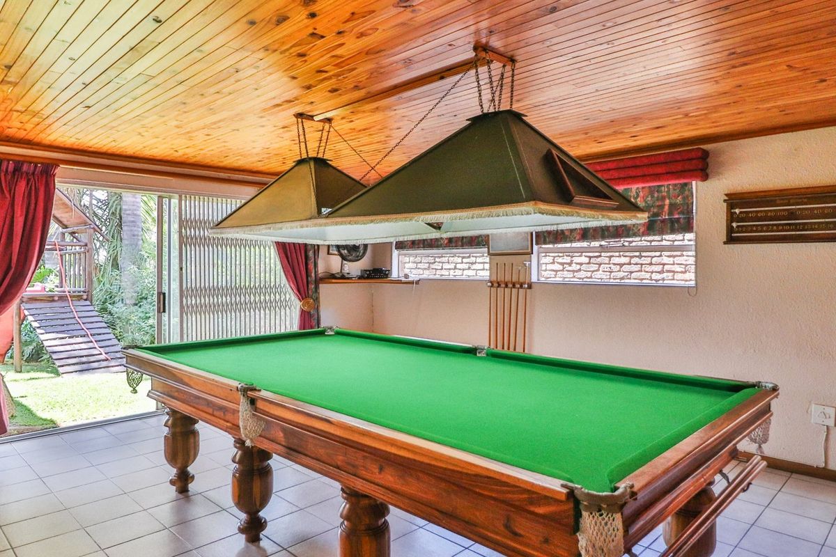 Spacious entertainment room featuring a timber ceiling, tiled floors, and direct access to the garden through sliding glass doors.