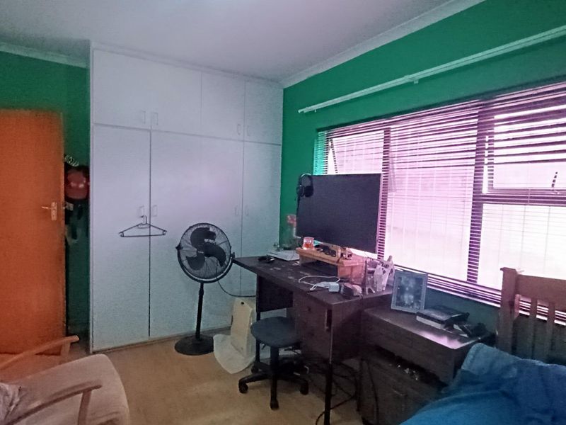 A bedroom featuring built-in cupboards, large windows with venetian blinds, and coving detail.
