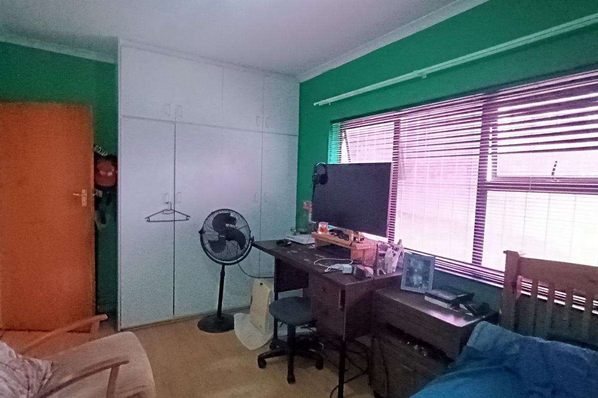 A bedroom featuring built-in cupboards, large windows with venetian blinds, and coving detail.