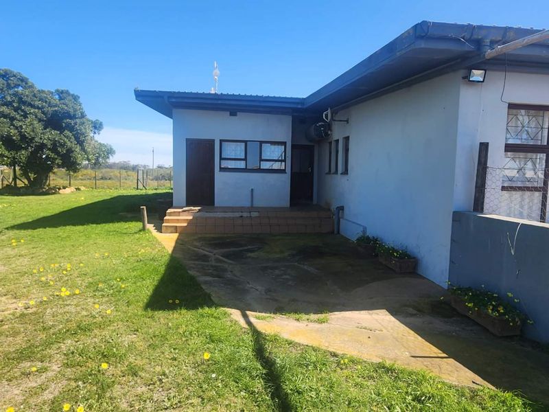 Rear view of the farm property featuring a concrete patio area, security bars on windows, and access to the surrounding garden space.