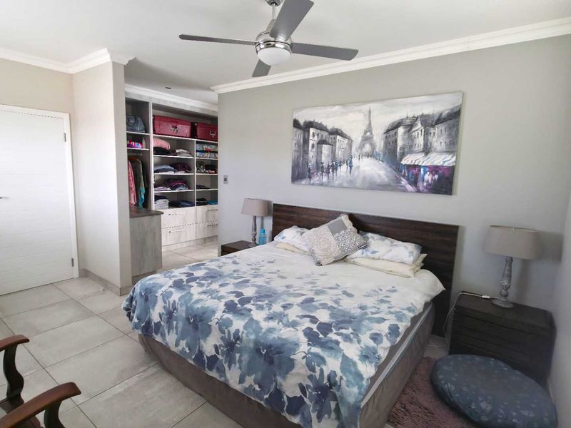 Spacious bedroom featuring tiled flooring, a ceiling fan, and integrated built-in cupboard storage space.