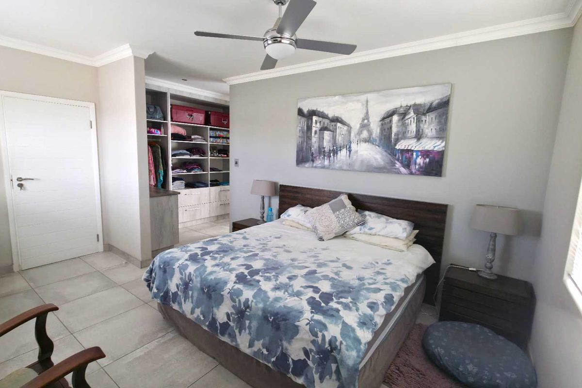 Spacious bedroom featuring tiled flooring, a ceiling fan, and integrated built-in cupboard storage space.