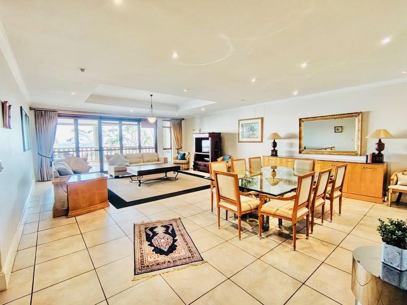 Spacious open-plan living and dining area featuring large sliding glass doors, tiled flooring, recessed ceiling details, and built-in cabinetry.