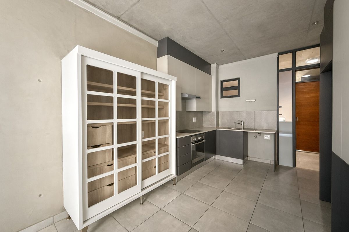 Modern kitchen featuring sleek cabinetry, built-in oven and hob, stainless steel sink, and contemporary tiled flooring with an industrial exposed concrete ceiling.