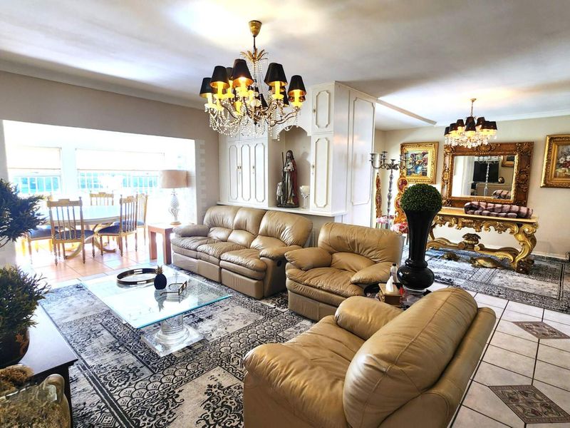 Spacious open-plan living and dining area featuring ceramic tile flooring, built-in cabinetry, and decorative chandeliers, offering a versatile layout for family living.