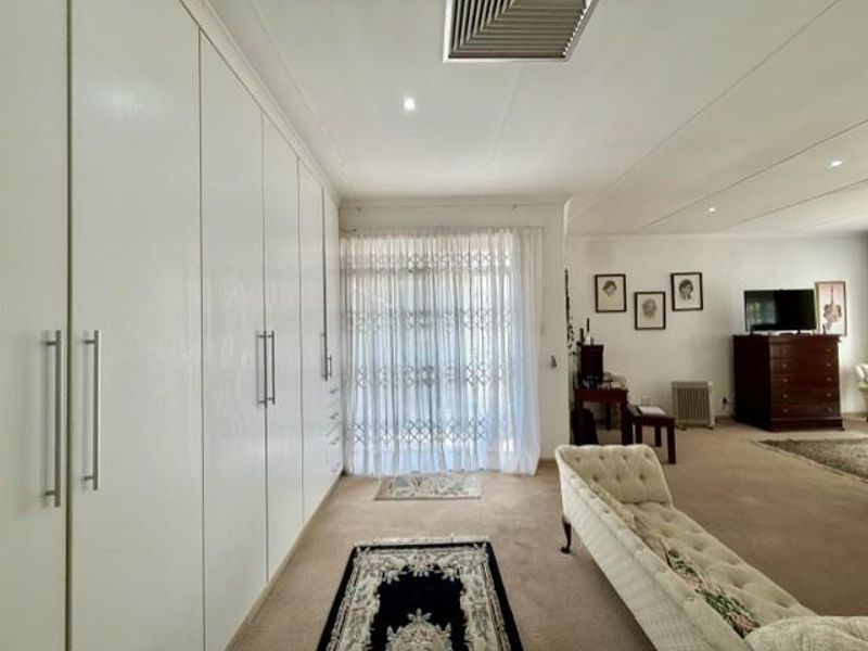 A spacious living area featuring extensive built-in cabinetry, recessed lighting, and a security gate leading to the exterior.