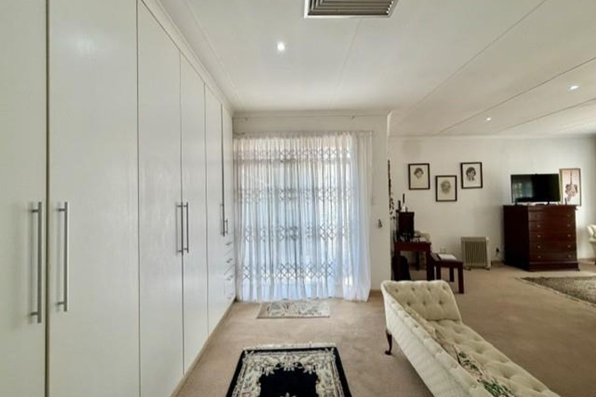 A spacious living area featuring extensive built-in cabinetry, recessed lighting, and a security gate leading to the exterior.