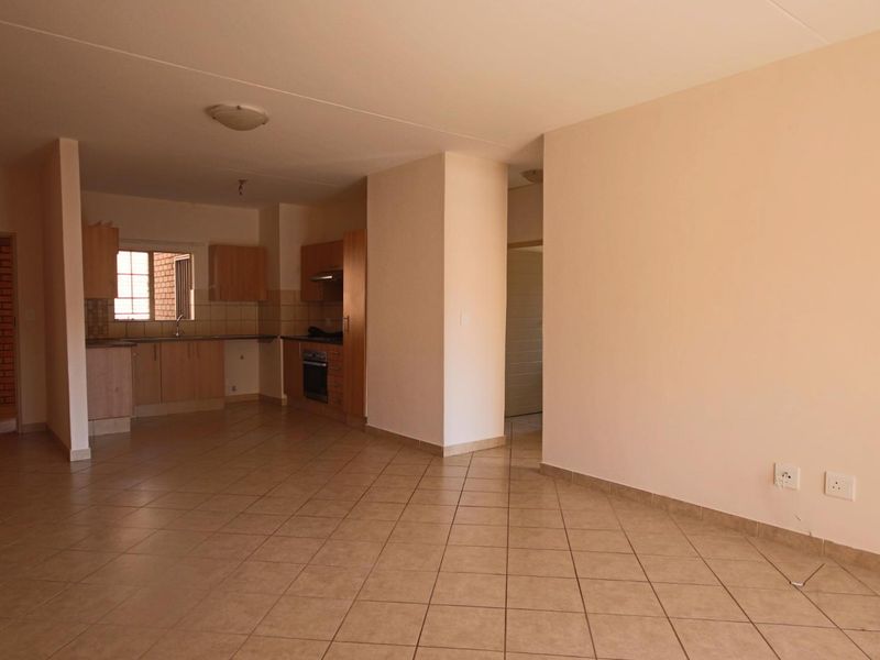 Spacious open-plan living area featuring tiled flooring and a functional kitchen with built-in cabinetry, oven, and extractor fan.