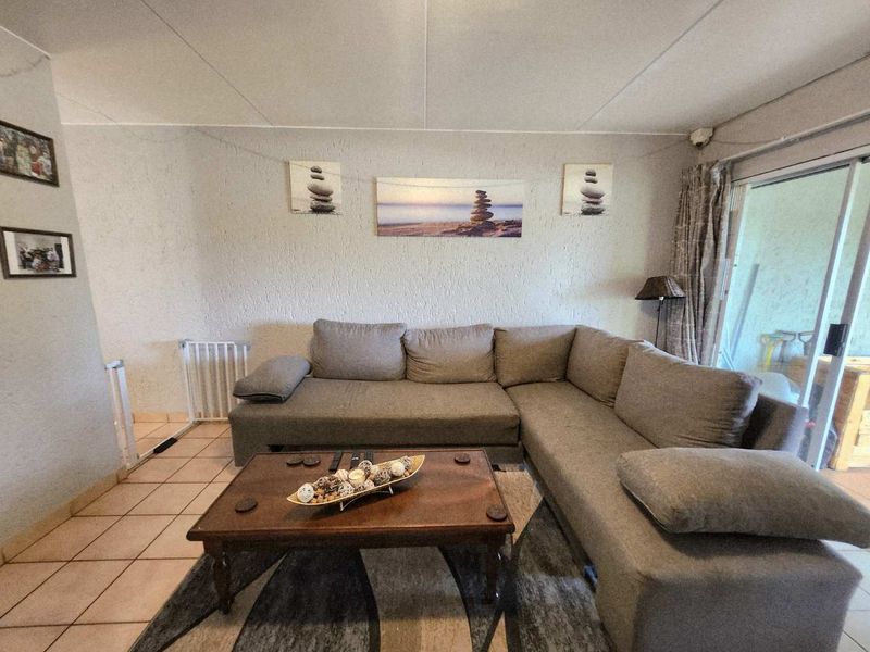 A comfortable living room featuring tiled flooring and a large sliding glass door providing access to the outdoor area.