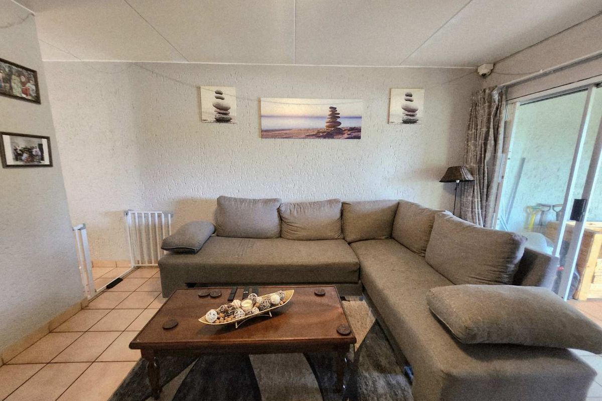 A comfortable living room featuring tiled flooring and a large sliding glass door providing access to the outdoor area.