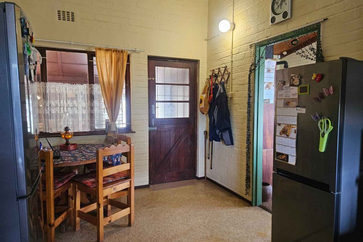A functional kitchen area featuring exposed brick walls, timber-framed door and window, and vinyl flooring, offering potential for a modern renovation.