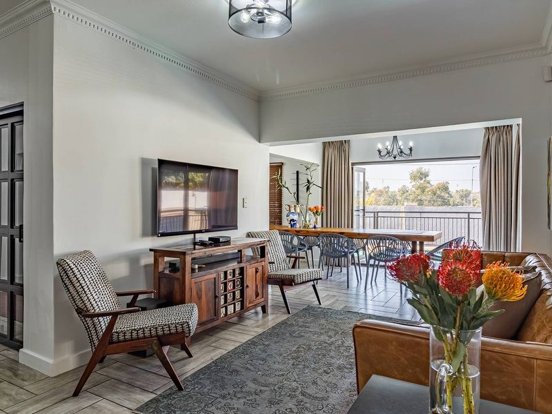 Spacious open-plan living and dining area featuring tiled flooring, crown molding, and large sliding doors leading to an outdoor balcony.