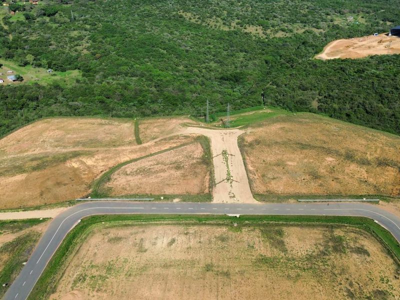 Aerial view of a large, cleared industrial development site featuring paved road access and surrounding natural vegetation.