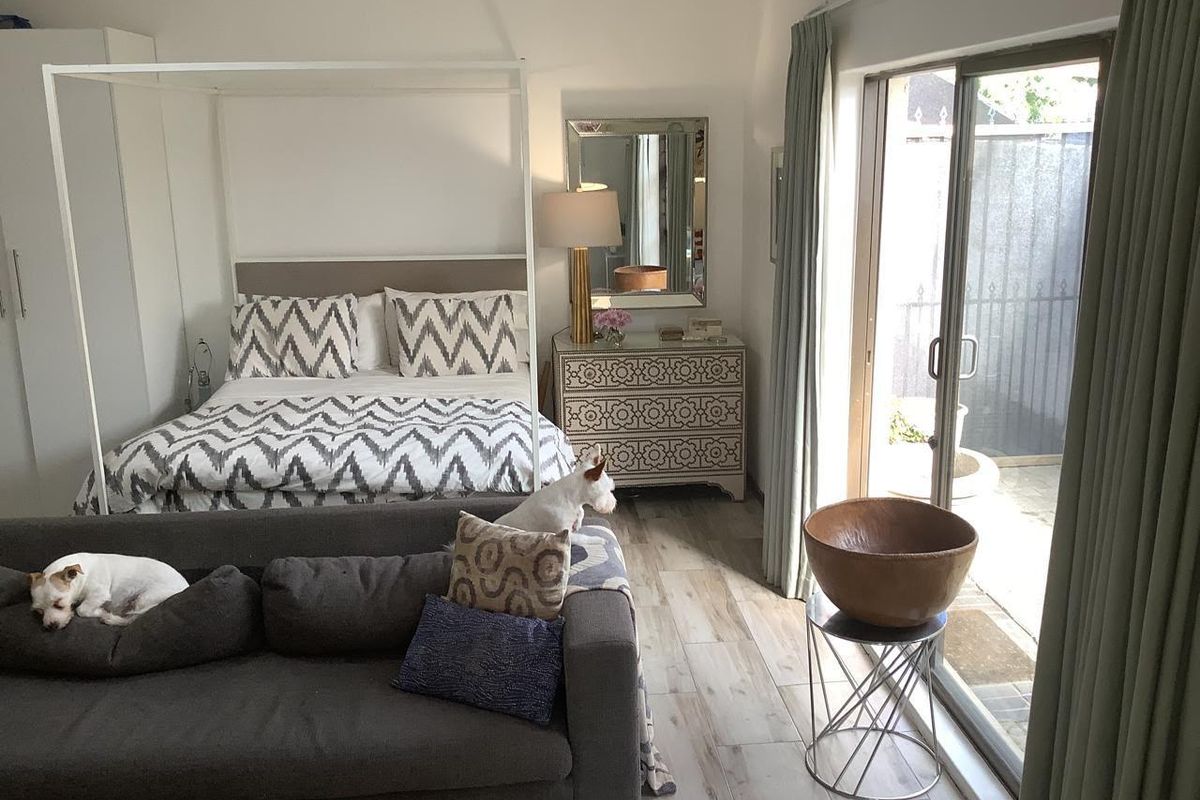 A bright bedroom featuring wood-look tile flooring and large sliding glass doors providing direct access to an outdoor patio area.