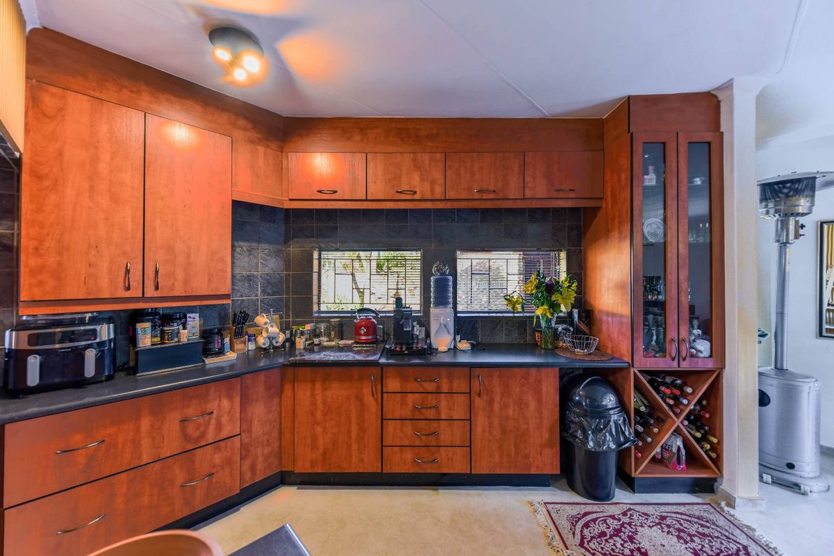 A functional kitchen featuring warm-toned wooden cabinetry, dark laminate countertops, a tiled backsplash, and a dedicated built-in wine storage rack.