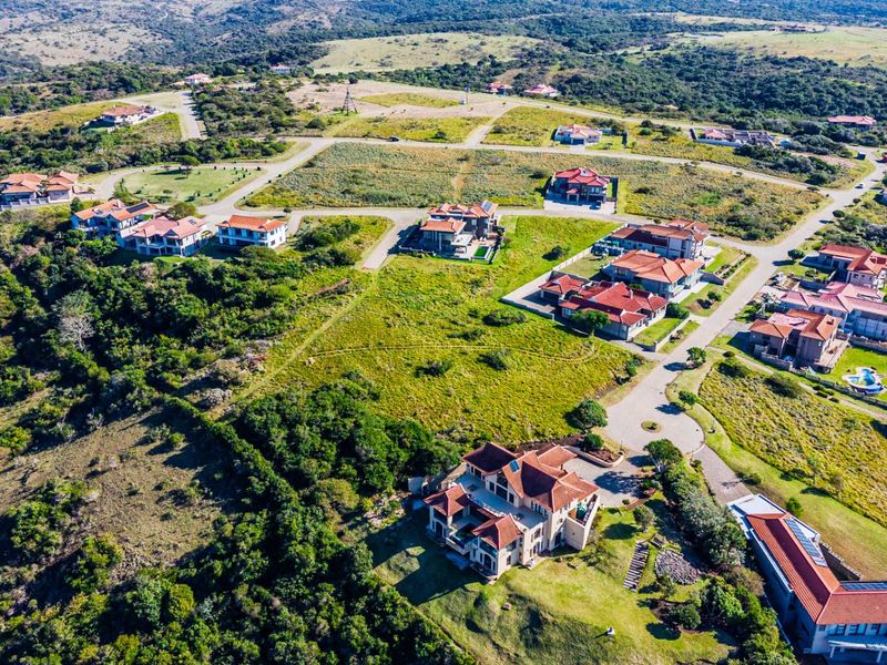 An aerial view of a residential estate development featuring established homes, paved road infrastructure, and surrounding natural landscape.