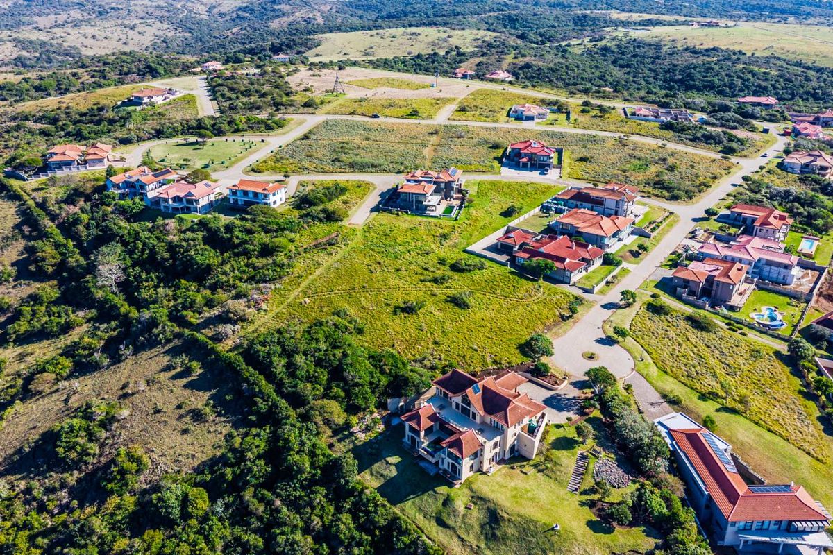 An aerial view of a residential estate development featuring established homes, paved road infrastructure, and surrounding natural landscape.