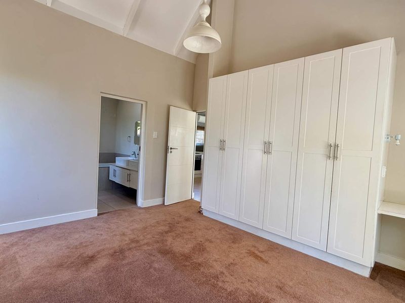 Spacious bedroom featuring high vaulted ceilings, extensive built-in cabinetry, and direct access to an en-suite bathroom.