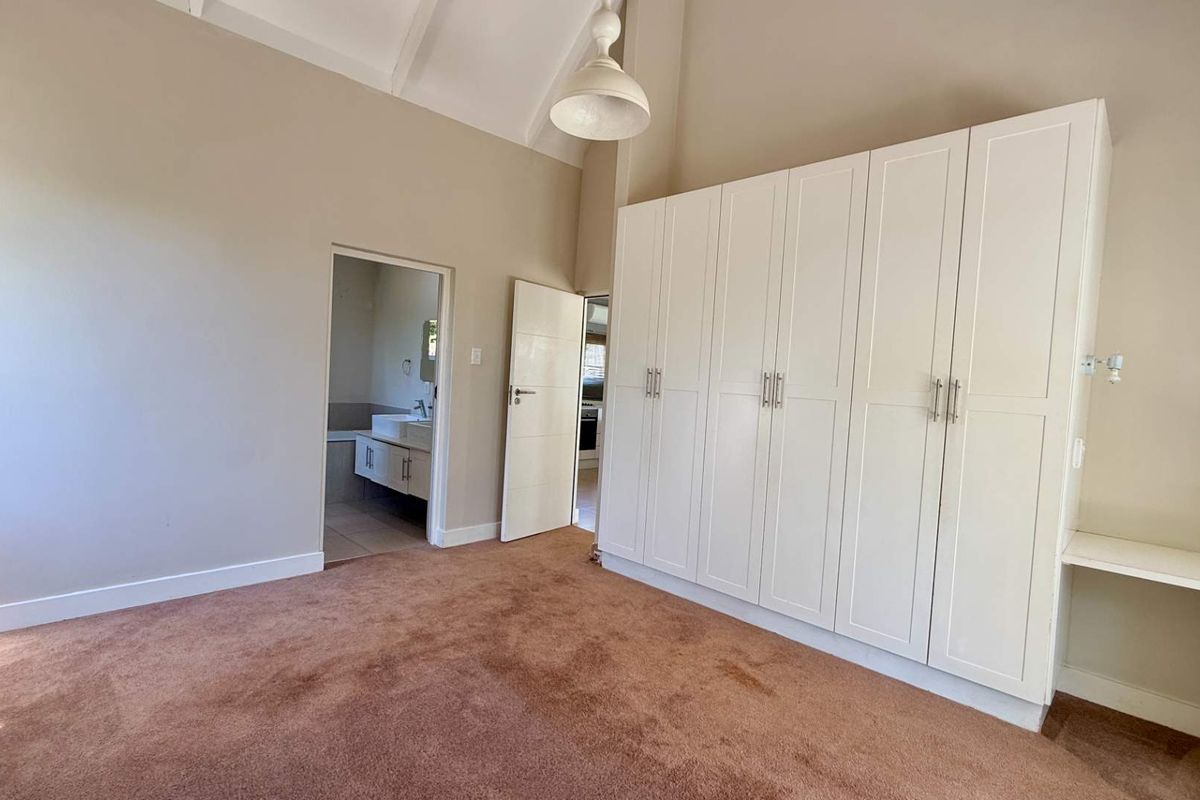 Spacious bedroom featuring high vaulted ceilings, extensive built-in cabinetry, and direct access to an en-suite bathroom.
