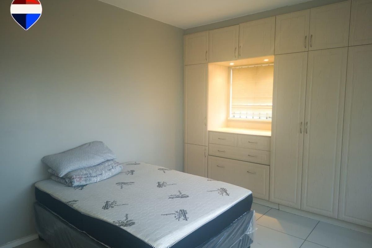 A bedroom featuring neutral tiled flooring and extensive built-in cabinetry with integrated lighting and a central vanity or desk area.