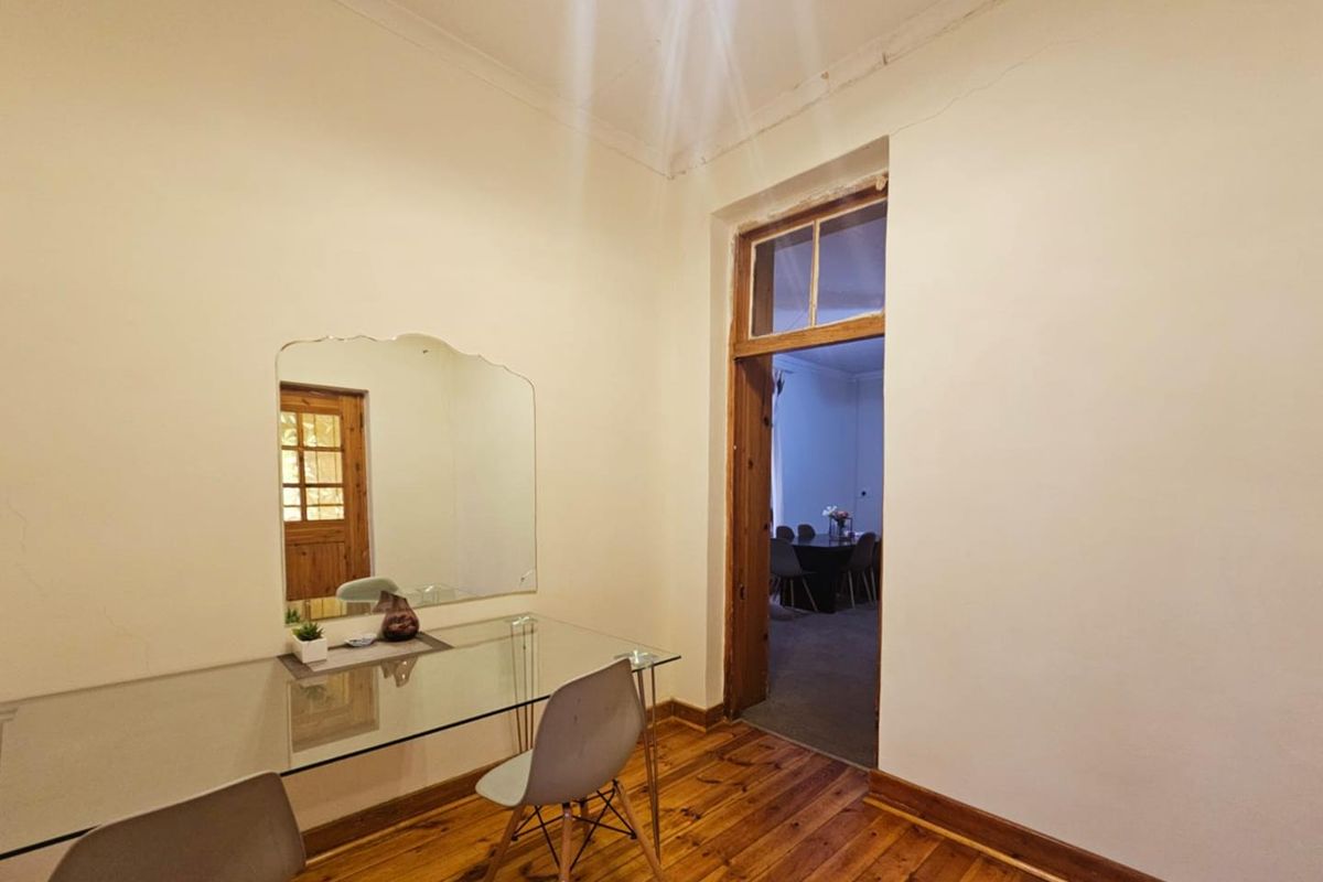 A bedroom featuring original timber flooring, high ceilings with crown molding, and a doorway leading to an adjacent living space.