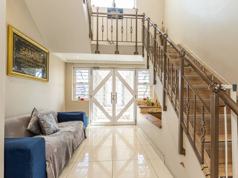 Bright entrance foyer featuring tiled flooring, a staircase with metal balustrades, and a secure double-door entry.