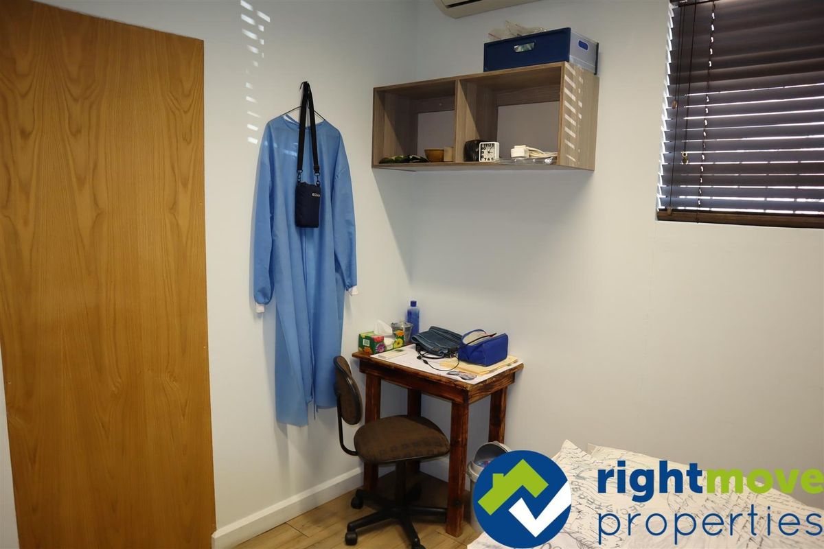 A compact office space featuring laminate flooring, wall-mounted shelving, and an air conditioning unit, suitable for a private workspace.