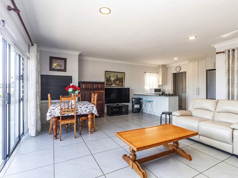 Spacious open-plan living and dining area featuring tiled floors, recessed lighting, and direct access to an outdoor patio through large sliding glass doors.