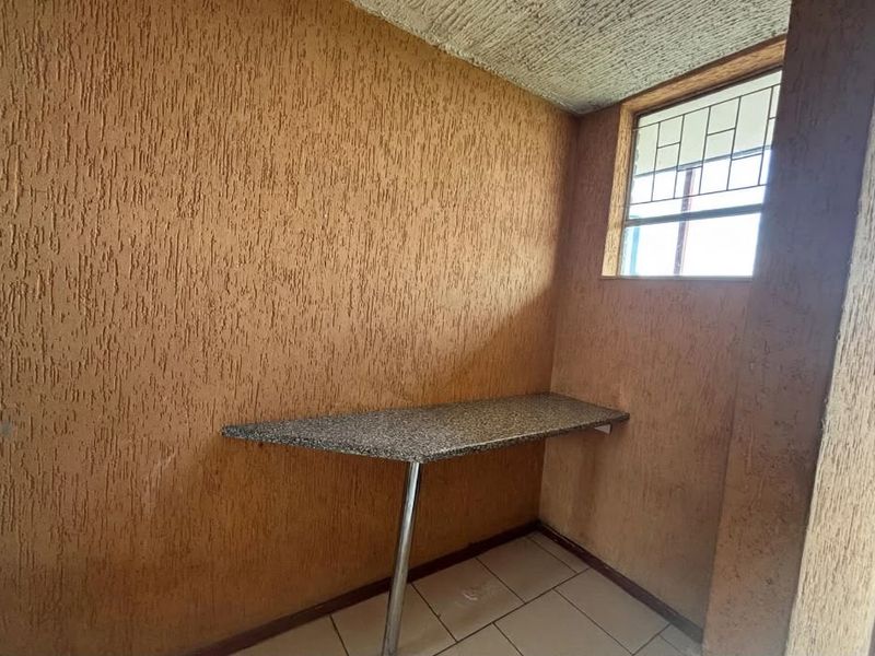 A small utility space featuring a granite countertop, tiled flooring, and textured walls, suitable for a laundry or prep area.