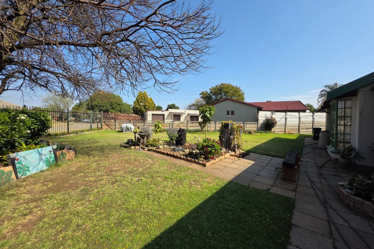 A spacious rear garden featuring a paved walkway, established lawn, and secure perimeter fencing, offering a private outdoor area.