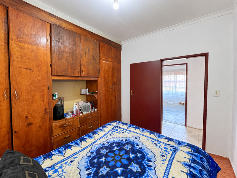 Bedroom featuring extensive built-in wooden cabinetry and a doorway leading to an adjacent room with tiled flooring.