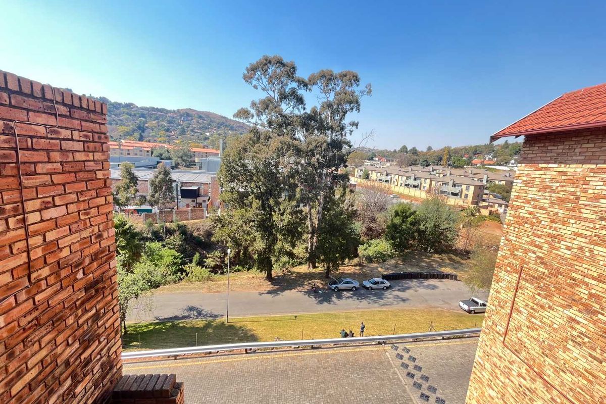 Elevated view overlooking the surrounding neighbourhood, street, and landscaped grounds from the apartment balcony.