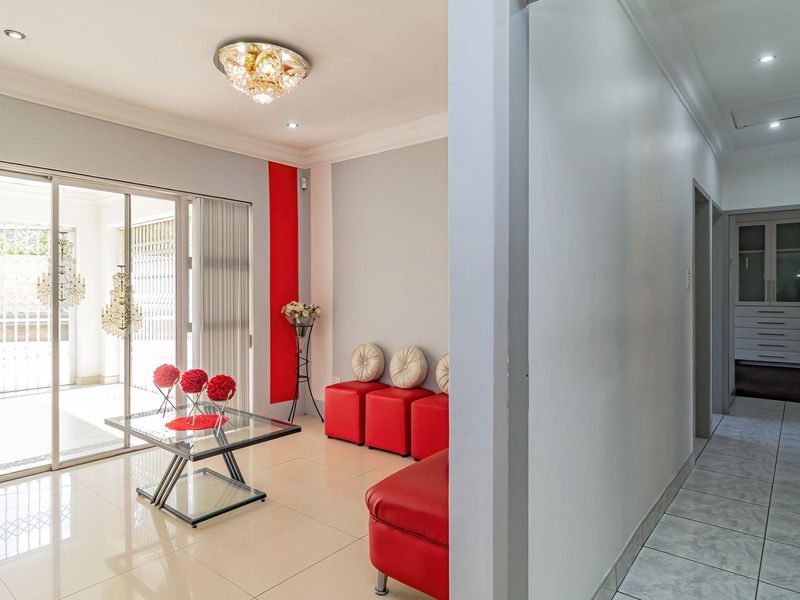 Bright living area featuring large sliding glass doors, neutral tiled flooring, and decorative ceiling lighting, providing seamless access to the outdoor patio space.