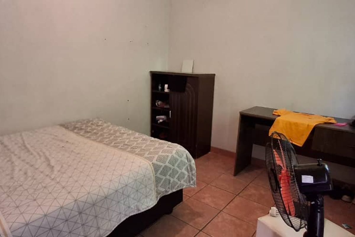 A simple bedroom featuring tiled flooring and plain walls, providing a functional space for rest.